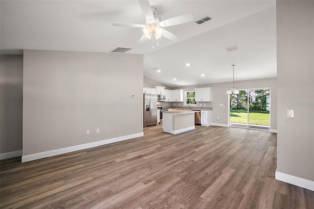 unfurnished living room with baseboards, visible vents, a ceiling fan, wood finished floors, and vaulted ceiling