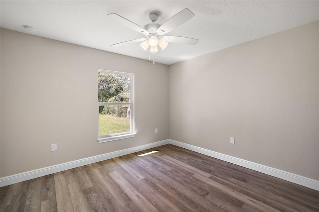 empty room featuring dark wood-style floors, ceiling fan, a textured ceiling, and baseboards