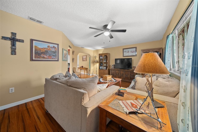 living area with arched walkways, dark wood-style flooring, visible vents, ceiling fan, and a textured ceiling