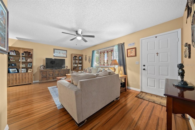 living area with baseboards, a textured ceiling, a ceiling fan, and dark wood-style flooring