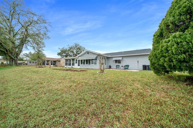 back of property with a patio area, a sunroom, central AC, and a lawn