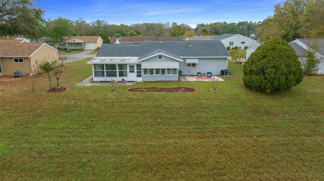 rear view of house with a sunroom, a patio area, a lawn, and central AC unit