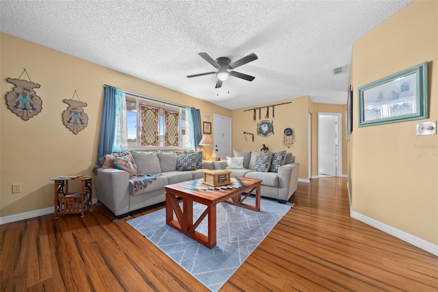 living area featuring a textured ceiling, visible vents, dark wood-style flooring, a ceiling fan, and baseboards