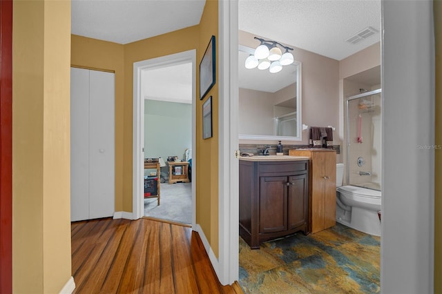 bathroom featuring a textured ceiling, toilet, baseboards, visible vents, and vanity