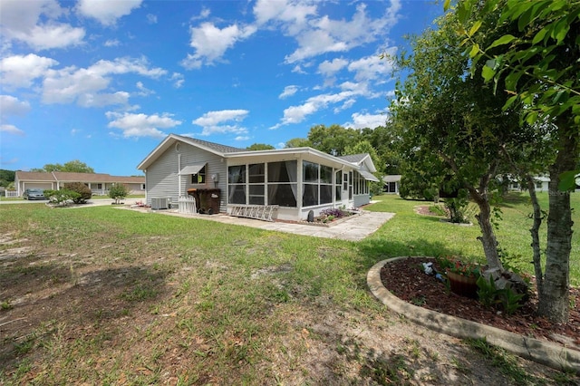 back of house with a sunroom, a lawn, and central AC