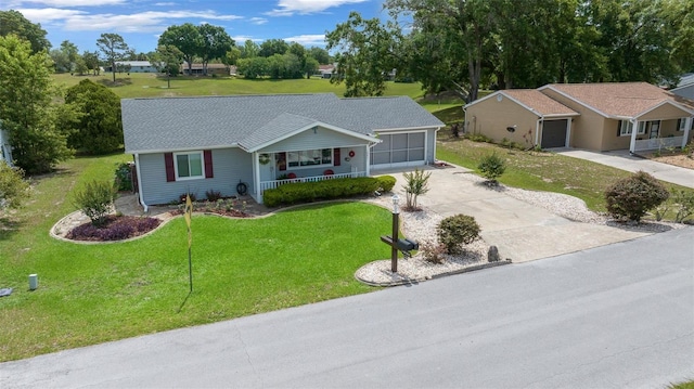 single story home featuring covered porch, an attached garage, concrete driveway, a front yard, and a shingled roof