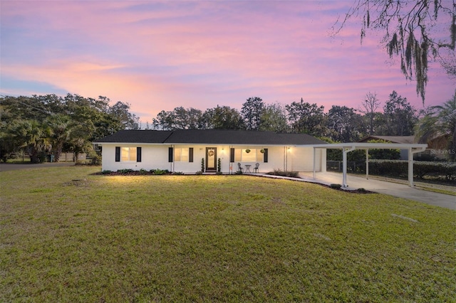 ranch-style house with an attached carport, a lawn, and driveway