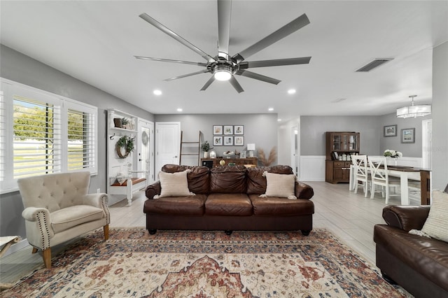 living room featuring ceiling fan with notable chandelier, wood finished floors, visible vents, and recessed lighting