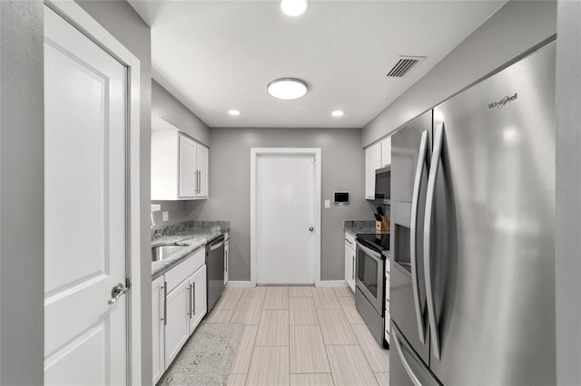 kitchen with light stone counters, visible vents, baseboards, white cabinetry, and appliances with stainless steel finishes