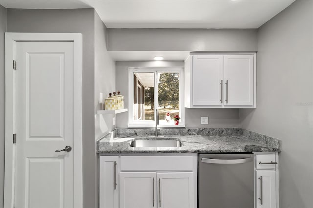 kitchen featuring dishwasher, a sink, light stone countertops, and white cabinets