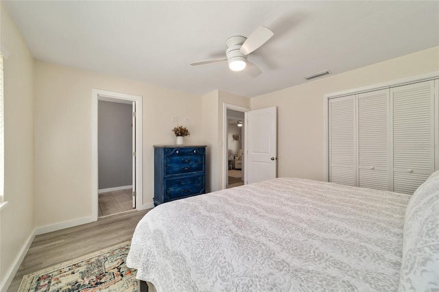 bedroom featuring baseboards, visible vents, a ceiling fan, wood finished floors, and a closet