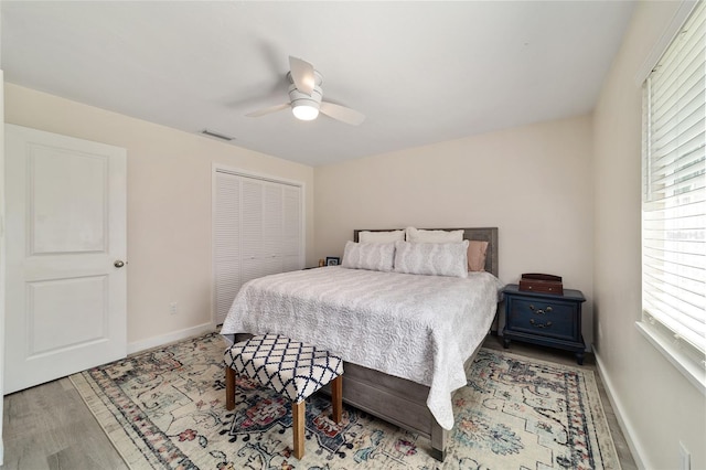 bedroom with a closet, visible vents, baseboards, and wood finished floors