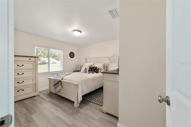 bedroom featuring light wood finished floors, visible vents, and baseboards