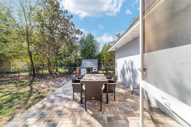 view of patio / terrace featuring a storage unit, outdoor dining area, an outdoor structure, and a fenced backyard