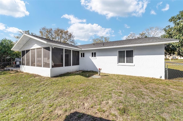 rear view of house with a sunroom, a yard, fence, and stucco siding