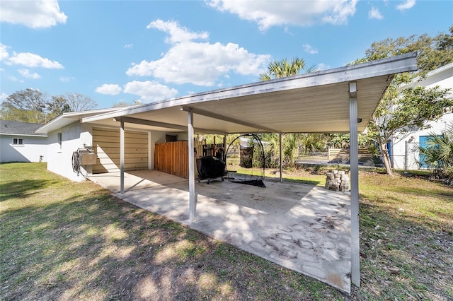 view of vehicle parking featuring a carport, fence, and driveway