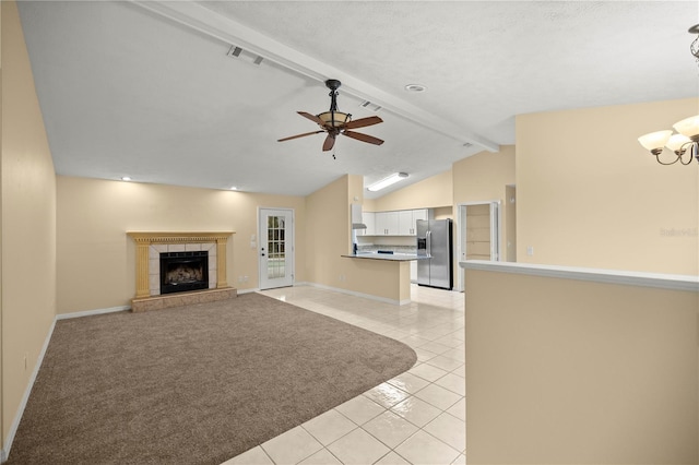 unfurnished living room featuring light tile patterned floors, visible vents, a tiled fireplace, lofted ceiling with beams, and ceiling fan with notable chandelier