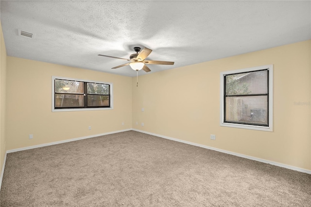 unfurnished room featuring carpet, visible vents, ceiling fan, a textured ceiling, and baseboards