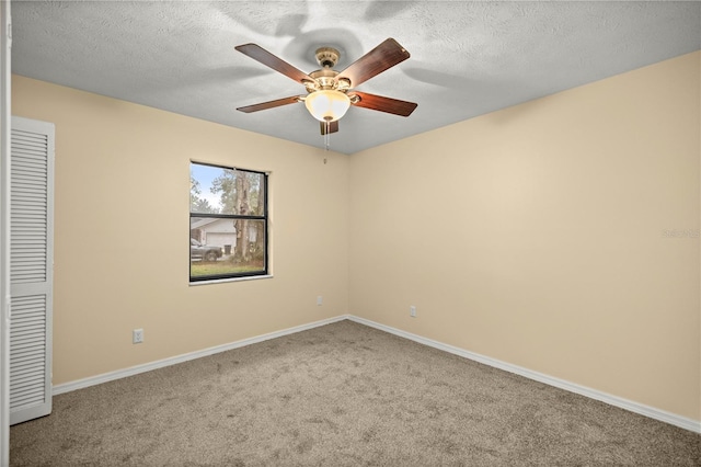 carpeted spare room featuring a textured ceiling, a ceiling fan, and baseboards