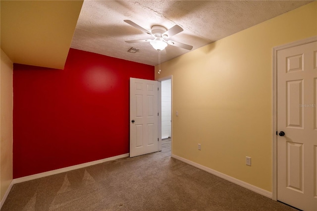 carpeted spare room with a ceiling fan, baseboards, and a textured ceiling