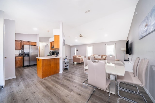 dining room with light hardwood / wood-style floors, vaulted ceiling, and ceiling fan