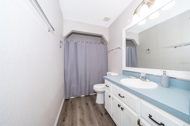 bathroom with toilet, vanity, and wood-type flooring