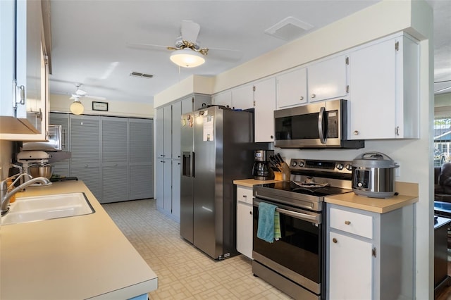 kitchen with appliances with stainless steel finishes, ceiling fan, sink, and white cabinetry