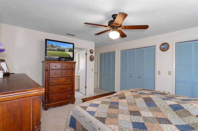 carpeted bedroom featuring ceiling fan and multiple closets