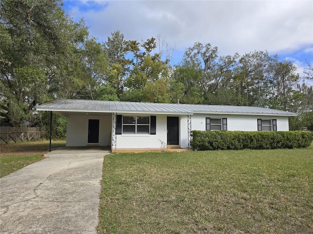 ranch-style home with stucco siding, concrete driveway, metal roof, an attached carport, and a front lawn