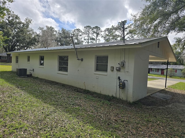 exterior space with central air condition unit, metal roof, and a lawn