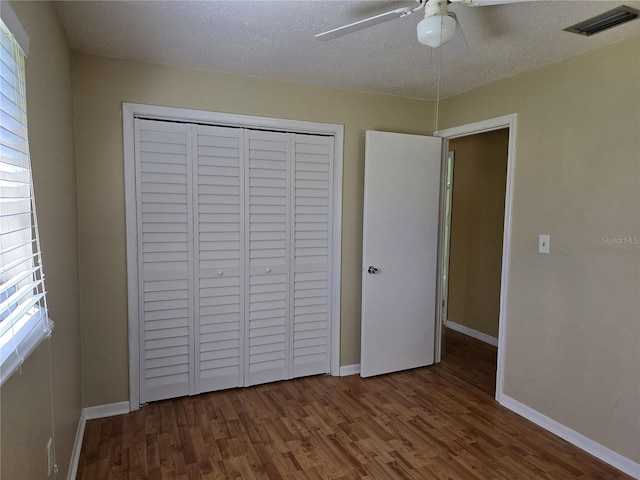 unfurnished bedroom with baseboards, visible vents, wood finished floors, a textured ceiling, and a closet