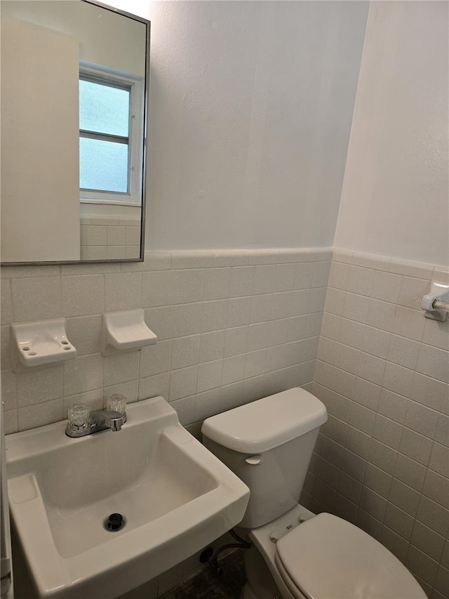 half bath featuring a wainscoted wall, a sink, and toilet