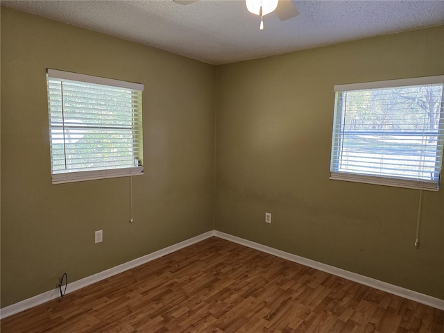 unfurnished room featuring a textured ceiling, baseboards, and wood finished floors