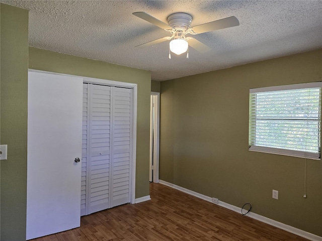 unfurnished bedroom with a textured ceiling, a closet, baseboards, and dark wood-type flooring