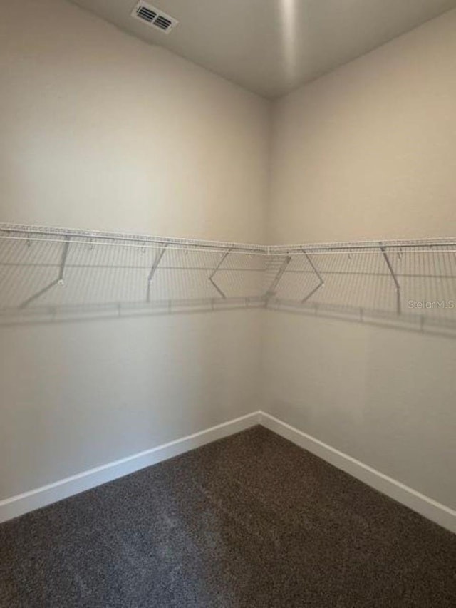 walk in closet featuring visible vents and dark carpet