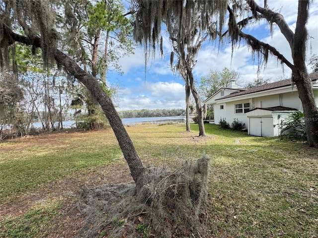 view of yard with an outbuilding, a water view, and a storage unit