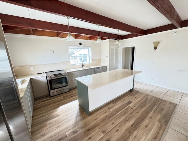 kitchen featuring appliances with stainless steel finishes, gray cabinets, a kitchen island, and pendant lighting