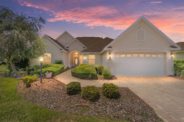 view of front of house with an attached garage, decorative driveway, and stucco siding