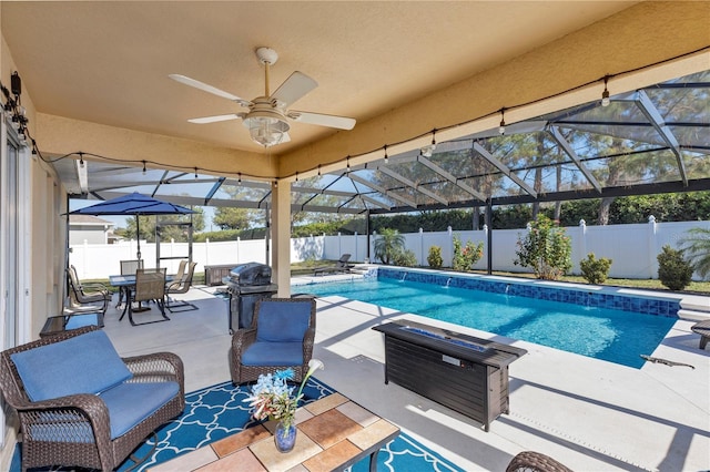 view of swimming pool with a patio area, area for grilling, ceiling fan, and glass enclosure