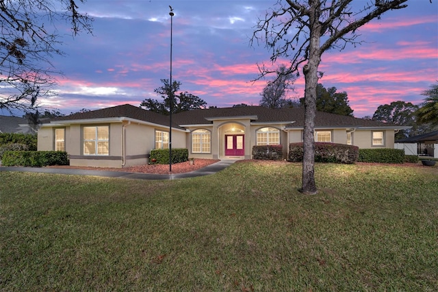 ranch-style home with a yard and stucco siding