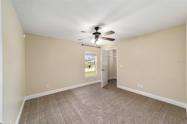 carpeted spare room with a ceiling fan, a textured ceiling, and baseboards