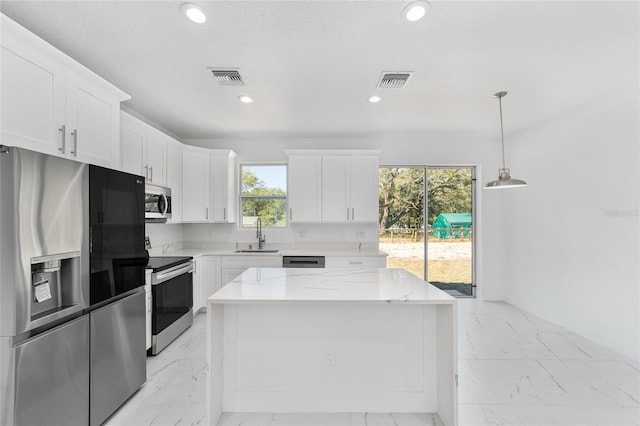 kitchen with stainless steel appliances, a center island, marble finish floor, and white cabinets