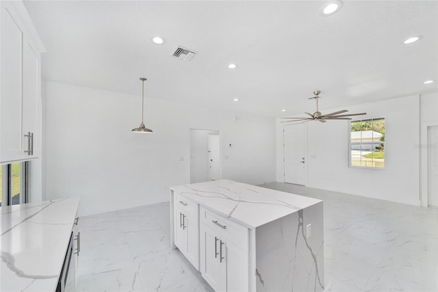 kitchen with open floor plan, hanging light fixtures, light stone countertops, and white cabinets