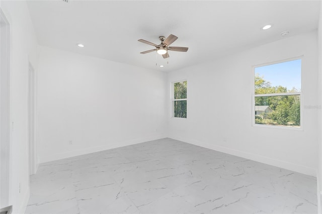 spare room featuring marble finish floor, plenty of natural light, and baseboards