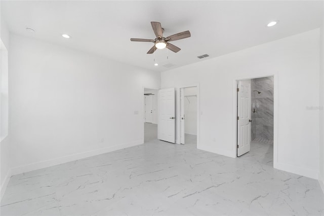 unfurnished bedroom featuring marble finish floor, baseboards, visible vents, and a walk in closet