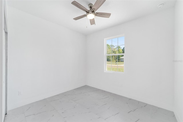 unfurnished room featuring marble finish floor, a ceiling fan, and baseboards