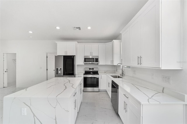 kitchen featuring visible vents, a center island, stainless steel appliances, white cabinetry, and a sink