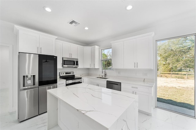 kitchen with white cabinets, marble finish floor, stainless steel appliances, and a center island