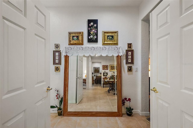 corridor featuring light tile patterned flooring and baseboards