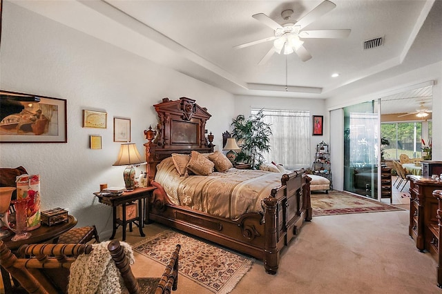 carpeted bedroom featuring ceiling fan, visible vents, a tray ceiling, and access to outside